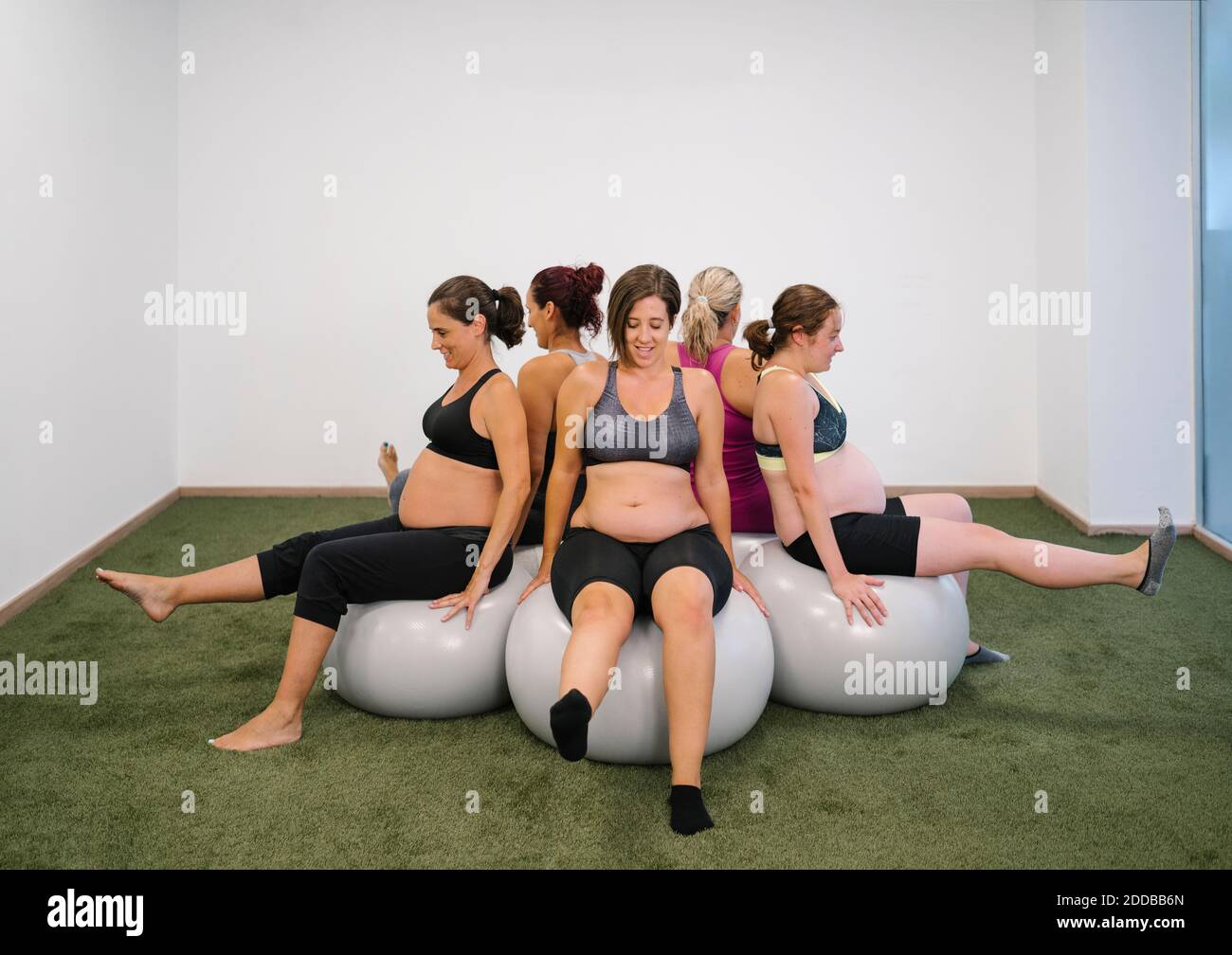 Donna incinta seduta sulla palla di fitness in cerchio rotondo con si può fare una tappa in uno studio di yoga Foto Stock