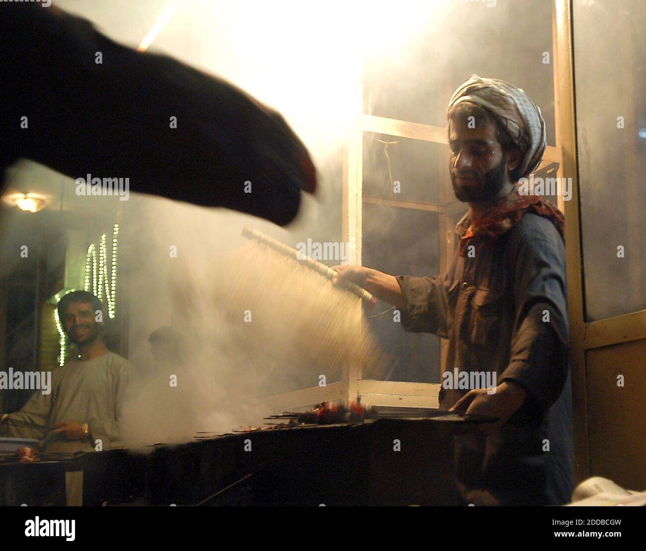 NO FILM, NO VIDEO, NO TV, NO DOCUMENTARIO - UN vedor di strada emerge da una nuvola di fumo come egli tifa il fuoco mentre cucina kabobs su Flower Street a Kabul, Afghanistan, Venerdì, 1 ottobre 2004. Foto di Aaron Suozzi/Fort Wayne News-Sentinel/KRT/ABACA Foto Stock