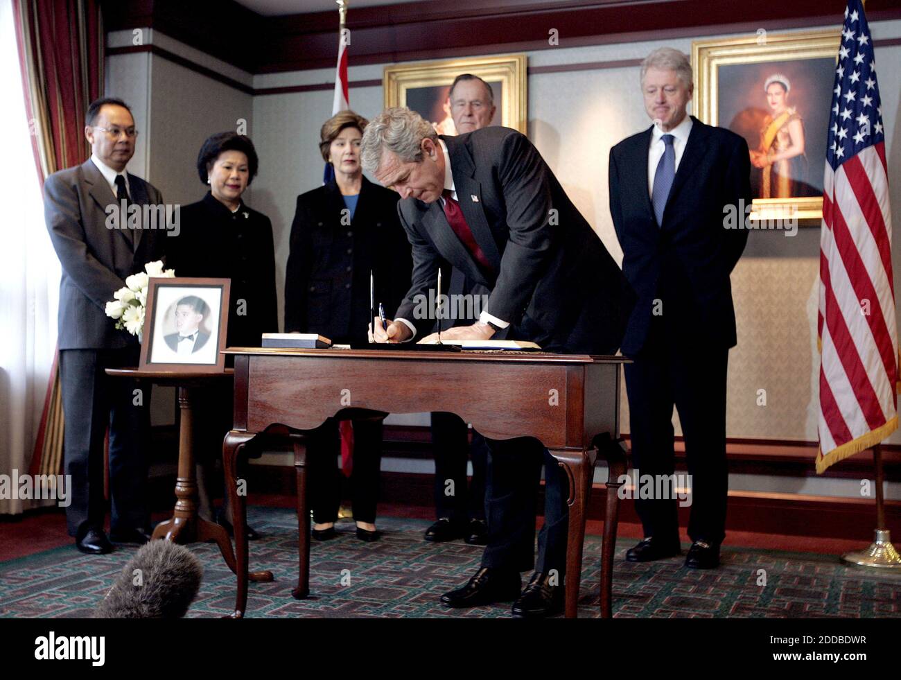 NO FILM, NO VIDEO, NO TV, NO DOCUMENTARY - il presidente degli Stati Uniti George W. Bush firma un libro di condoglianze come prima signora Laura Bush ed ex presidenti Bill Clinton e George H. Bush stare dietro di lui durante una visita all'ambasciata tailandese a Washington, 3 gennaio 2005. Il presidente Bush, insieme agli ex presidenti Bush e Clinton, ha visitato oggi quattro ambasciate di nazioni che sono state devastate dallo tsunami. A sinistra si trova l'ambasciatore tailandese Kasit Piromya e sua moglie Chintana. La foto sul tavolo è di Khun Poom Jensen, nipote del re tailandese, ucciso dallo tsunami a Phuket. Foto di CH Foto Stock