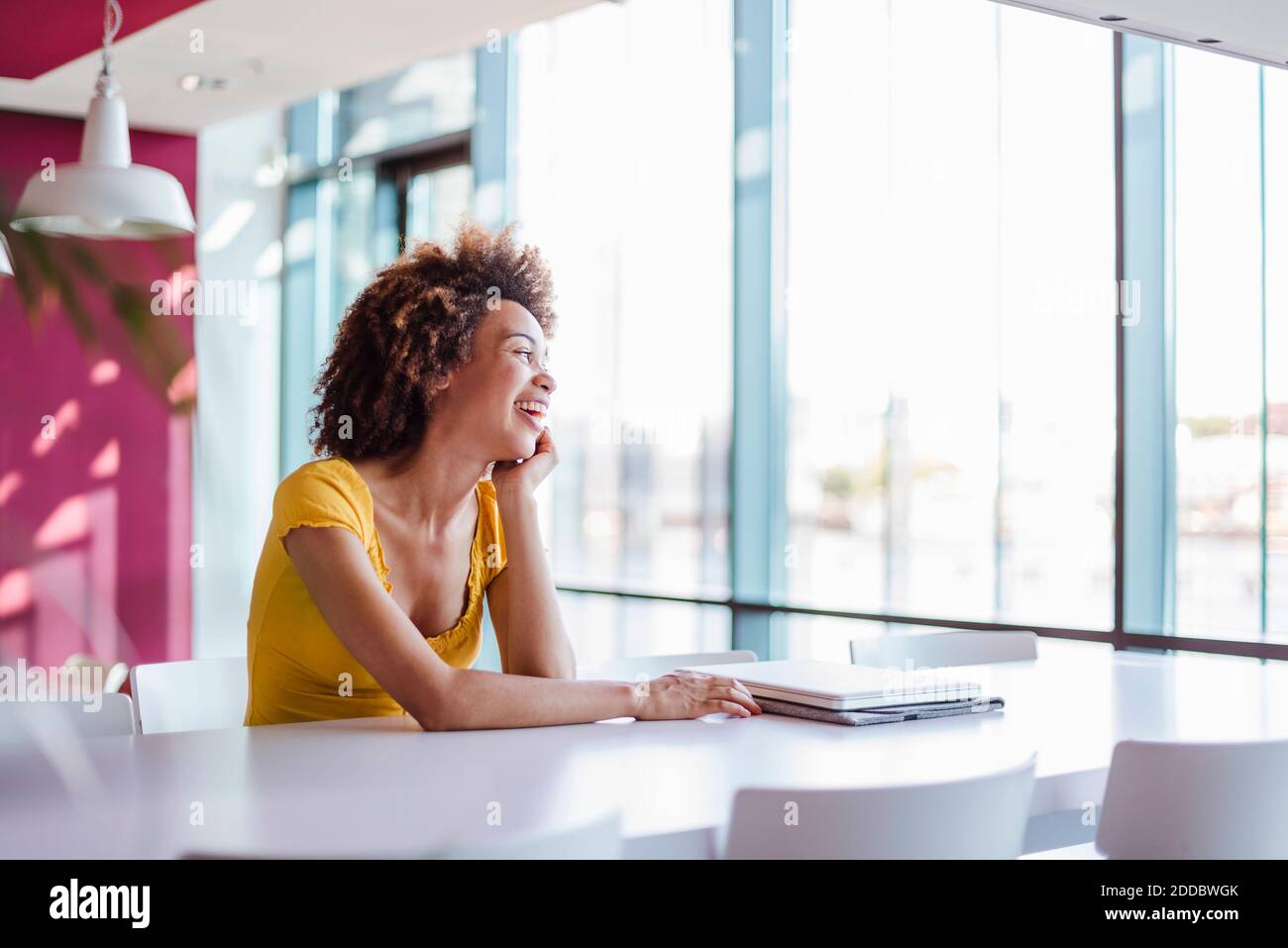 Giovane donna che lavora in un ufficio moderno, ridendo Foto Stock
