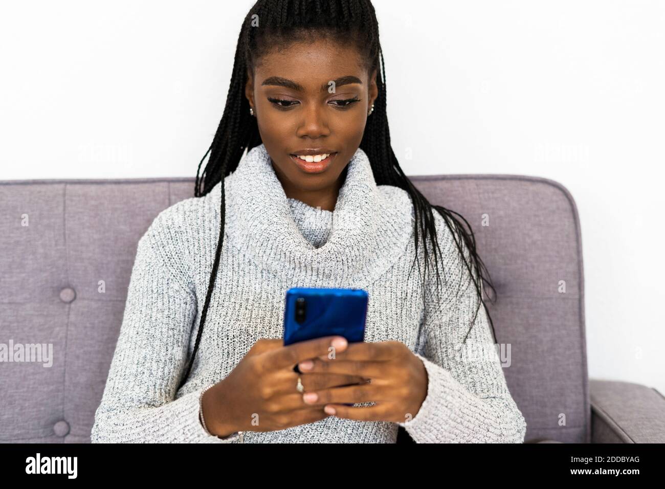 Messaggi di testo donna su smartphone mentre si è seduti a casa Foto Stock