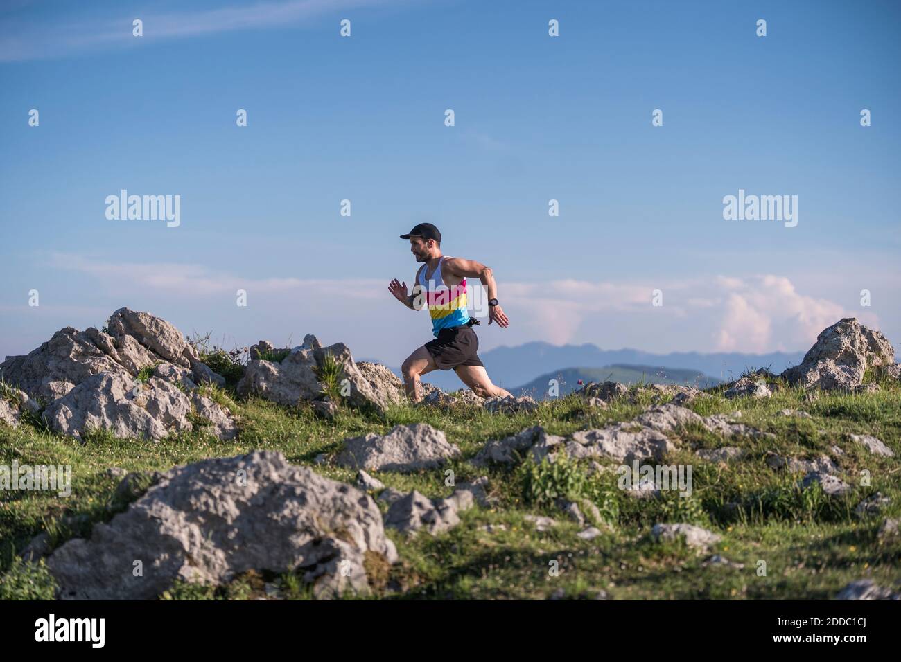 Sportivo che corre in montagna contro il cielo limpido Foto Stock