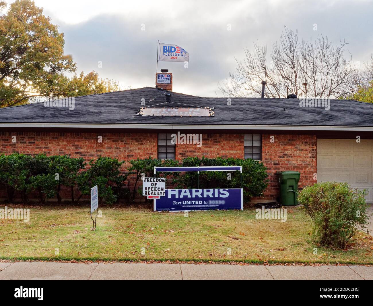 Arlington, Texas-24 Nov 2020: Il segno della campagna di Biden ha fatto la sua faccia nel prato dei proprietari di case in un sobborgo conservatore pro-Trump Texas fuori Dallas, Texas. Con l'ex vice-presidente degli Stati Uniti Joe Biden che ha vinto le elezioni presidenziali del 2020, un proprietario di abitazione pubblica "la libertà di parola realmente?" Firmi con la bandiera eletta di Biden che batte in alto fuori della portata dei supporti di Trump. Durante la posa Trump sostiene il cartello nel cortile anteriore, tagliando il nome di Biden. (Impossibile rimuovere il segno, ma in grado di tagliare il nome Biden) Foto Stock