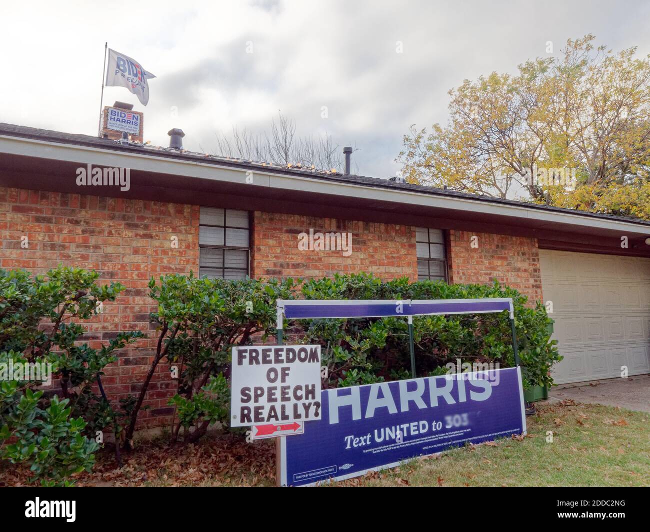 Arlington, Texas-24 Nov 2020: Il segno della campagna di Biden ha fatto la sua faccia nel prato dei proprietari di case in un sobborgo conservatore pro-Trump Texas fuori Dallas, Texas. Con l'ex vice-presidente degli Stati Uniti Joe Biden che ha vinto le elezioni presidenziali del 2020, un proprietario di abitazione pubblica "la libertà di parola realmente?" Firmi con la bandiera eletta di Biden che batte in alto fuori della portata dei supporti di Trump. Durante la posa Trump sostiene il cartello nel cortile anteriore, tagliando il nome di Biden. (Impossibile rimuovere il segno, ma in grado di tagliare il nome Biden) Foto Stock