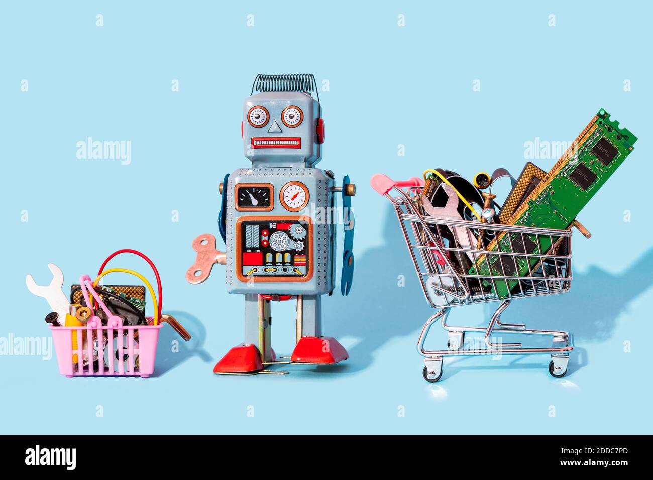 Studio di giocattoli robot vintage in piedi tra lo shopping in miniatura carrello e cestello riempiti con apparecchiature elettroniche Foto Stock