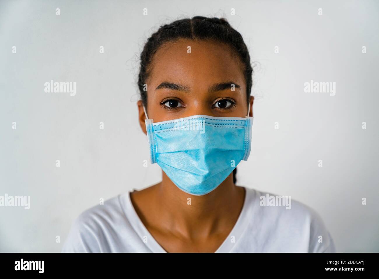 Adolescente ragazza indossare maschera protettiva viso in piedi contro la parete durante covid-19 Foto Stock