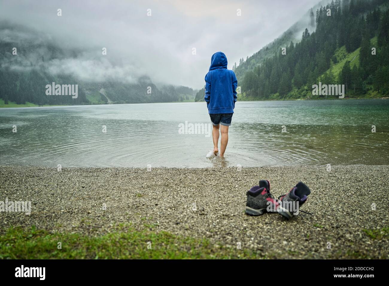 Donna che cammina sul lungolago durante la stagione delle piogge Foto Stock