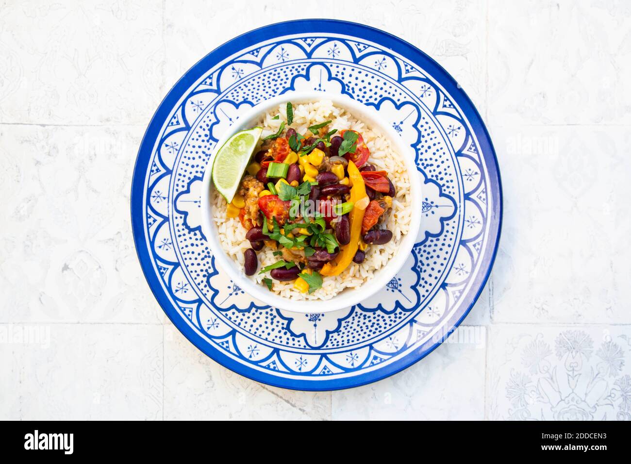 Ciotola di riso messicano con pomodori, peperone, tofu, fagioli, mais, scalione e lime Foto Stock