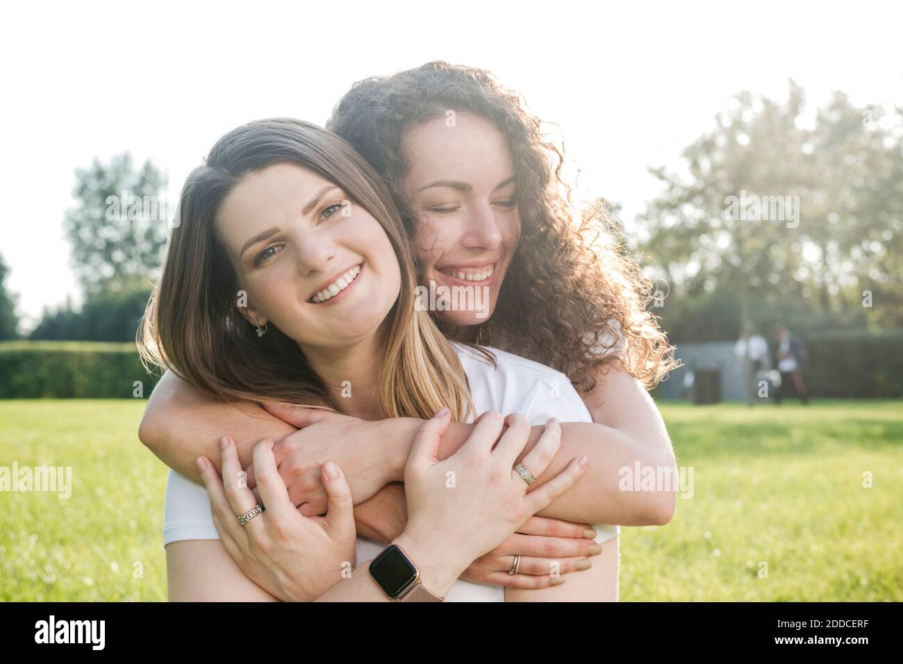 Bella donna che è abbracciata da sorridente giovane amica a. parcheggio Foto Stock