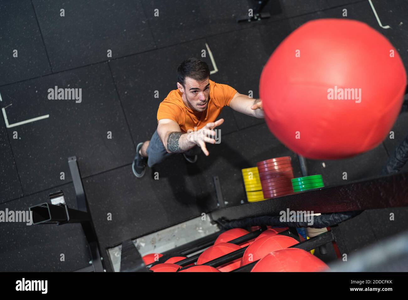 Uomo medio adulto che lancia palla di fitness mentre in piedi in palestra Foto Stock