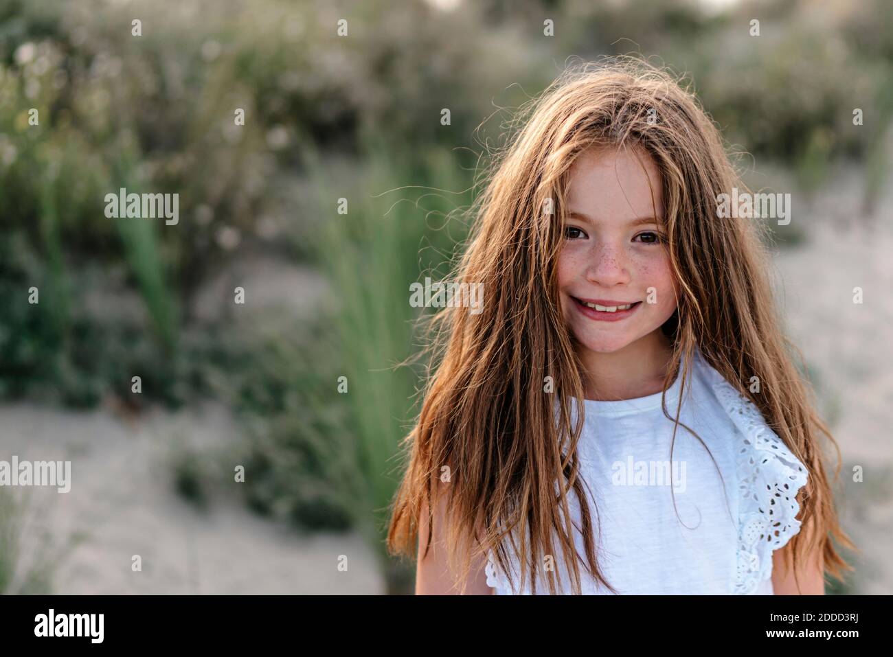 Marrone ragazza capelli in piedi sulla spiaggia in giornata di sole Foto Stock
