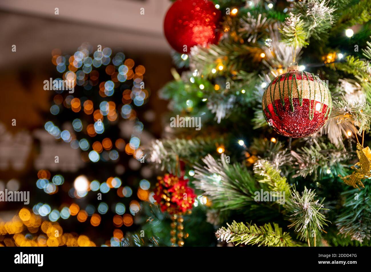 Primo piano di oro rosso boble sull'albero di natale. chirstmas con luci che si riflettono nella finestra a casa. Concetto di natale. Albero soggiorno. Foto Stock