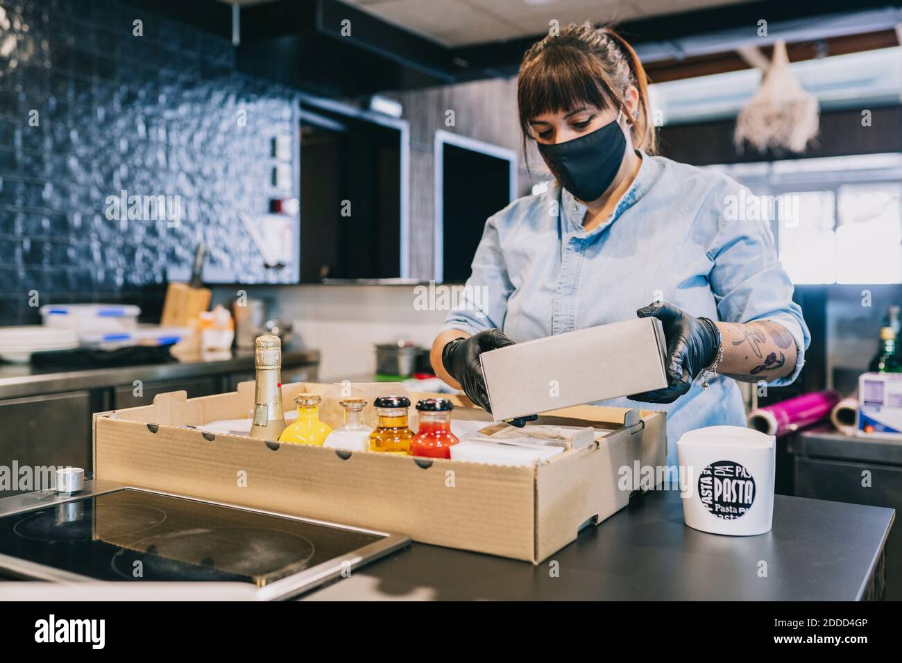 Chef femminile che organizza il cibo da togliere in scatola di cartone a. banco ristorante durante la pandemia Foto Stock