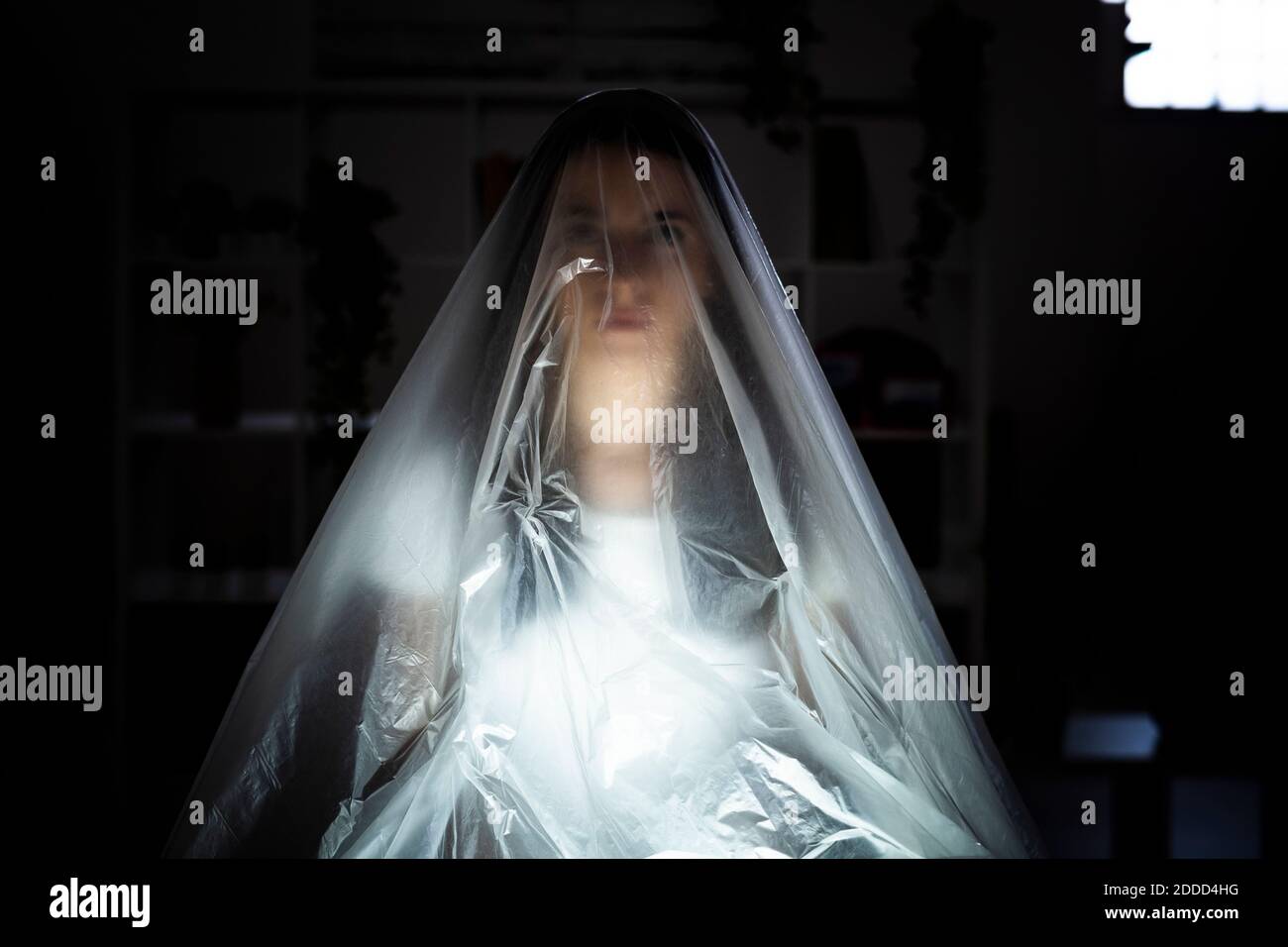 Donna preoccupata coperta di plastica nel timore di COVID-19 Foto Stock