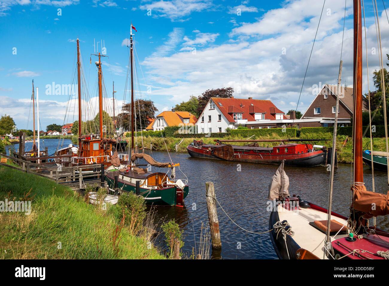 Germania, bassa Sassonia, Wittmund, Barche a vela ormeggiate lungo la riva del fiume Harle Foto Stock