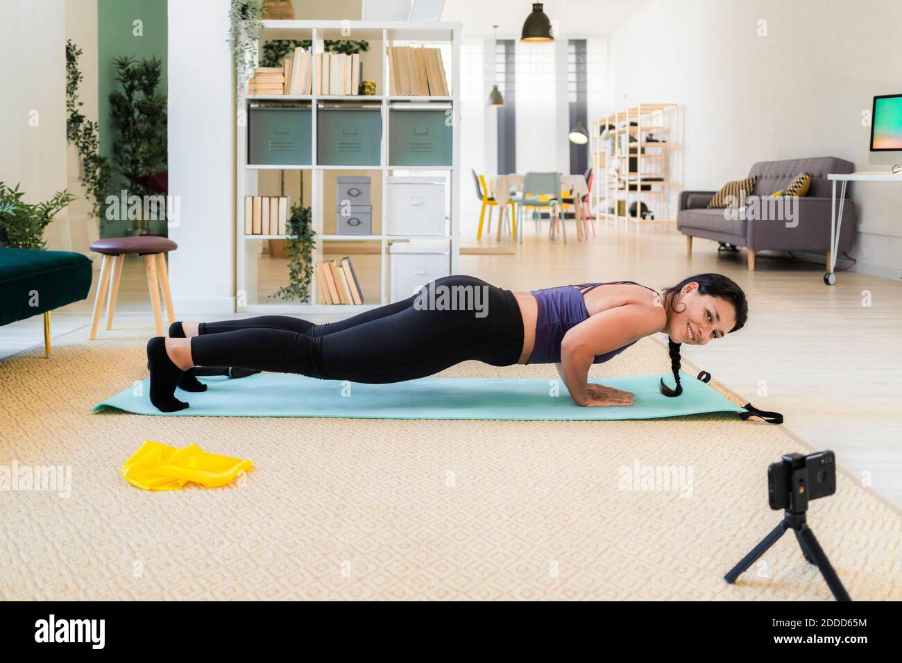Giovane donna del fitness che sorride durante la registrazione video in macchina fotografica spingi verso l'alto a casa Foto Stock