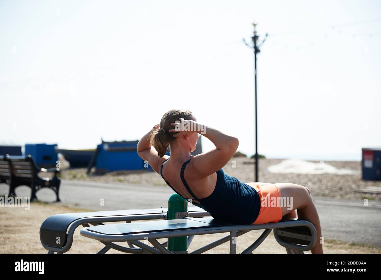 Donna matura che si siede su panchina durante la giornata di sole Foto Stock