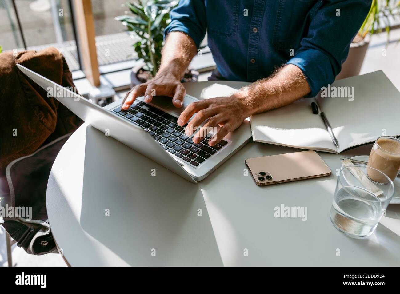 Freelance maschile che lavora su un computer portatile al tavolo nel bar Foto Stock