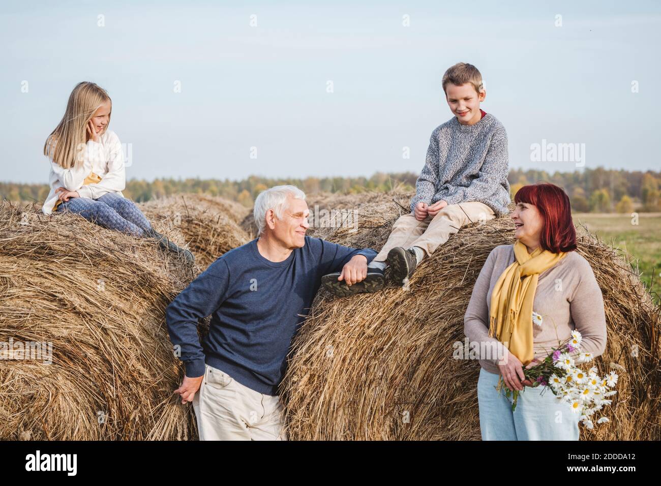 Nonni con nipoti seduti su balle di fieno Foto Stock
