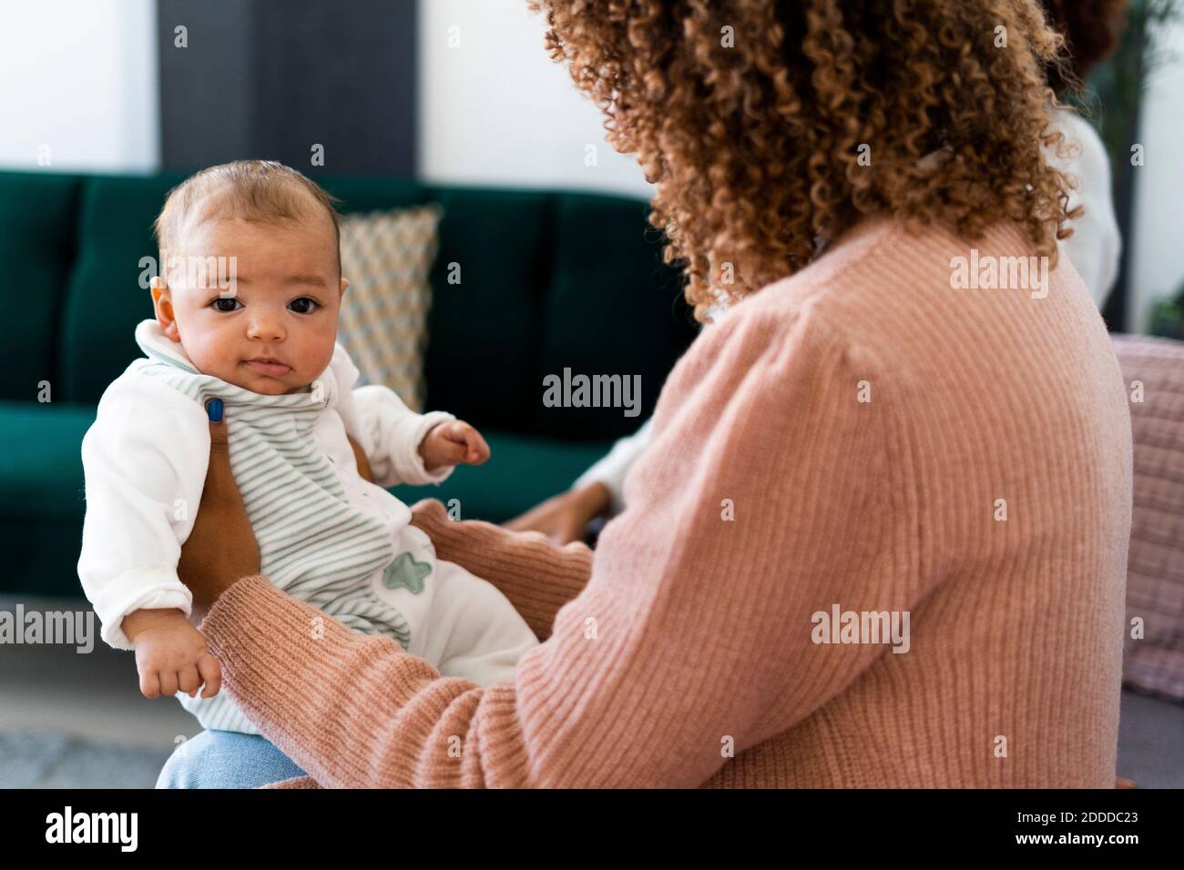 Madre che tiene la figlia del bambino mentre si siede a casa Foto Stock