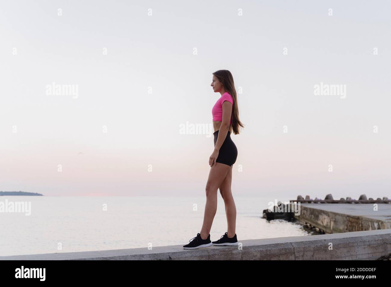 Atleta che ammira la vista del mare in piedi sulla parete di ritegno contro la luce cielo Foto Stock