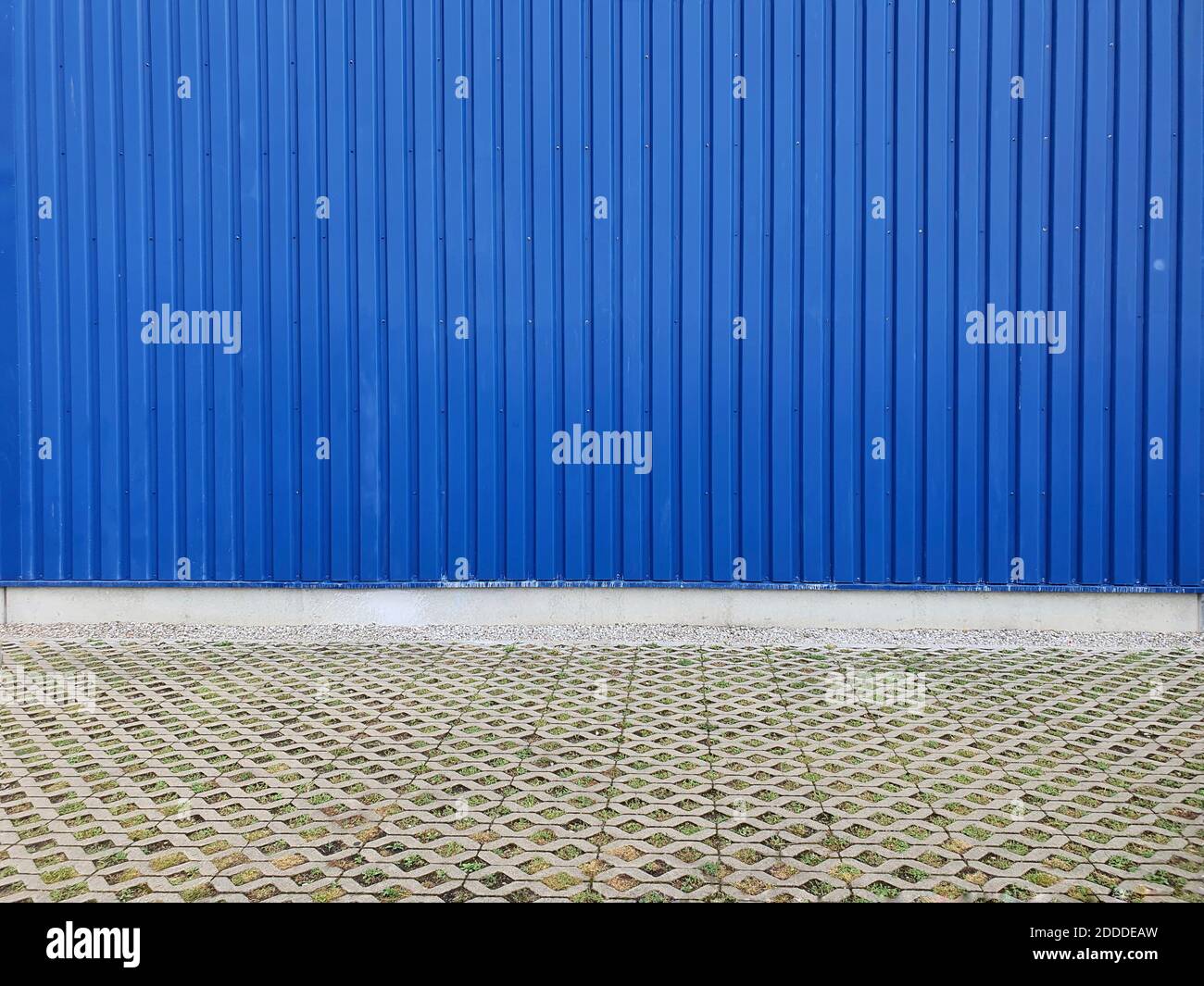 Terreno pavimentato di fronte alla parete di ferro corrugato blu Foto Stock