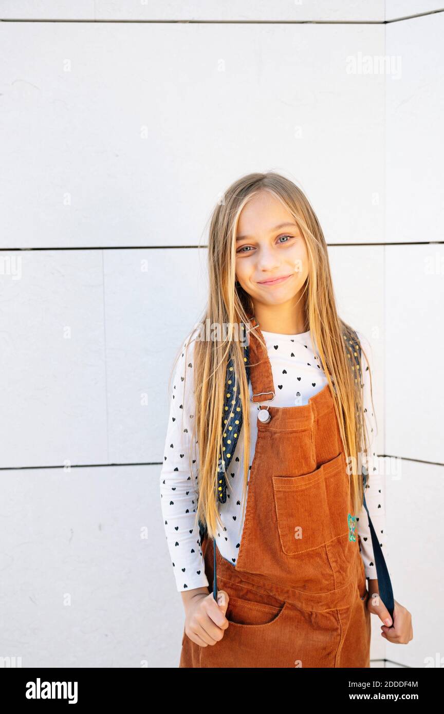 Bionda ragazza sorridente mentre si è in piedi contro il muro nella giornata di sole Foto Stock