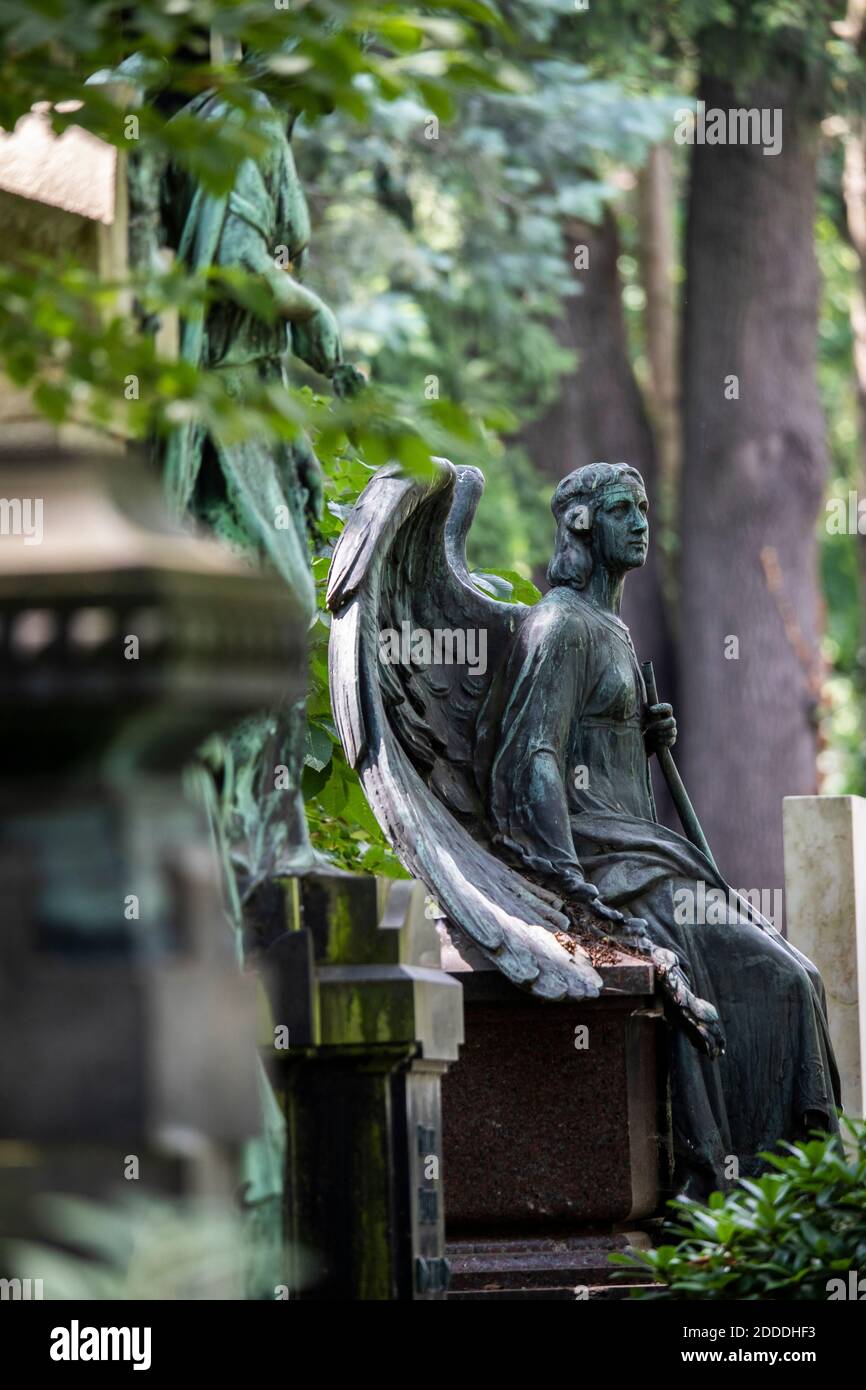 Statua di angelo intemperie seduto al bordo della tomba in cimitero Foto Stock