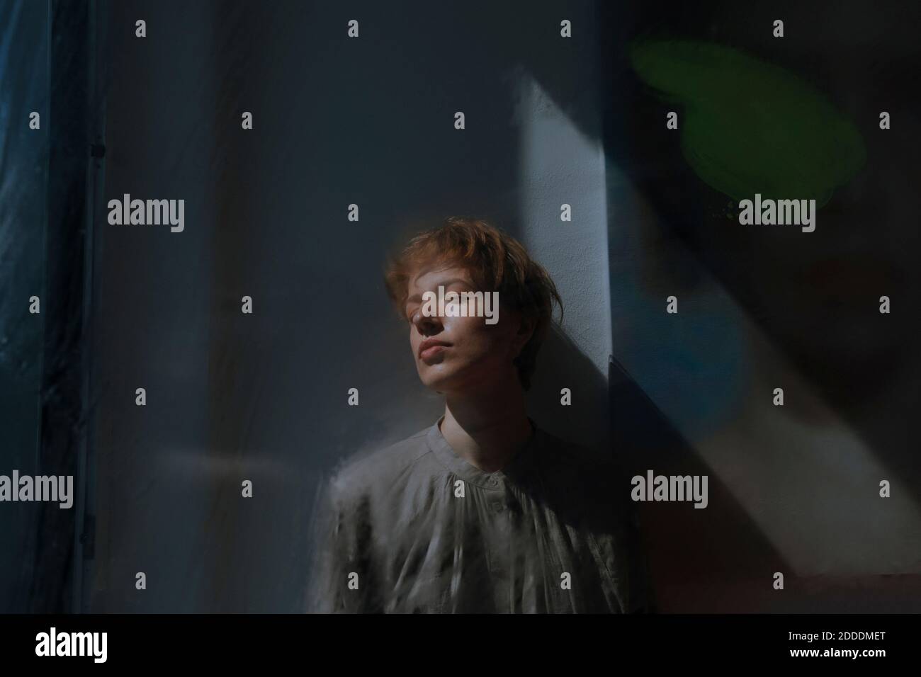 Artista femminile che si appoggia con gli occhi chiusi sulla parete nell'arte studio Foto Stock