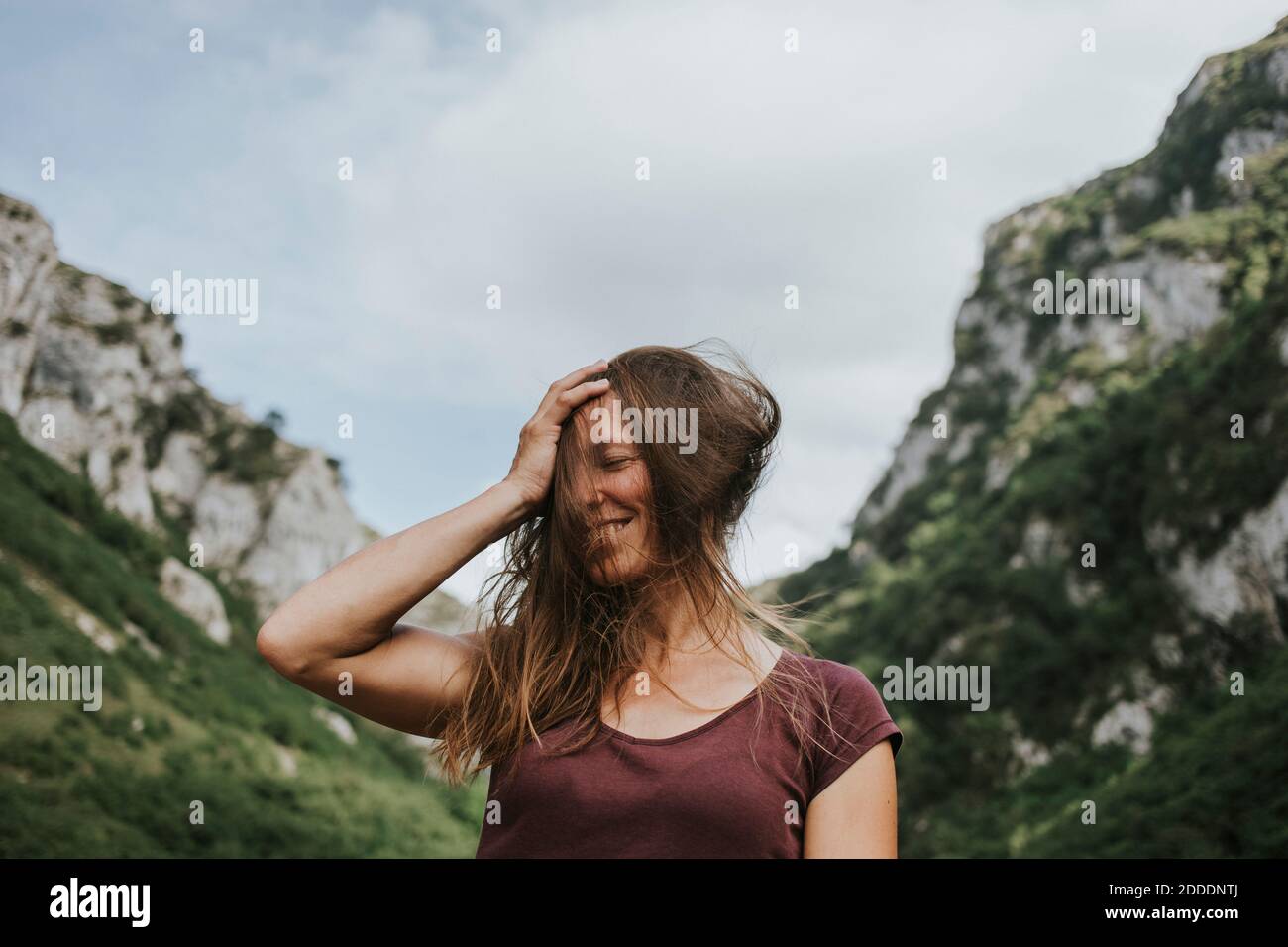 Happy donna Trekker con capelli castani lunghi tosati contro la montagna intervallo Foto Stock