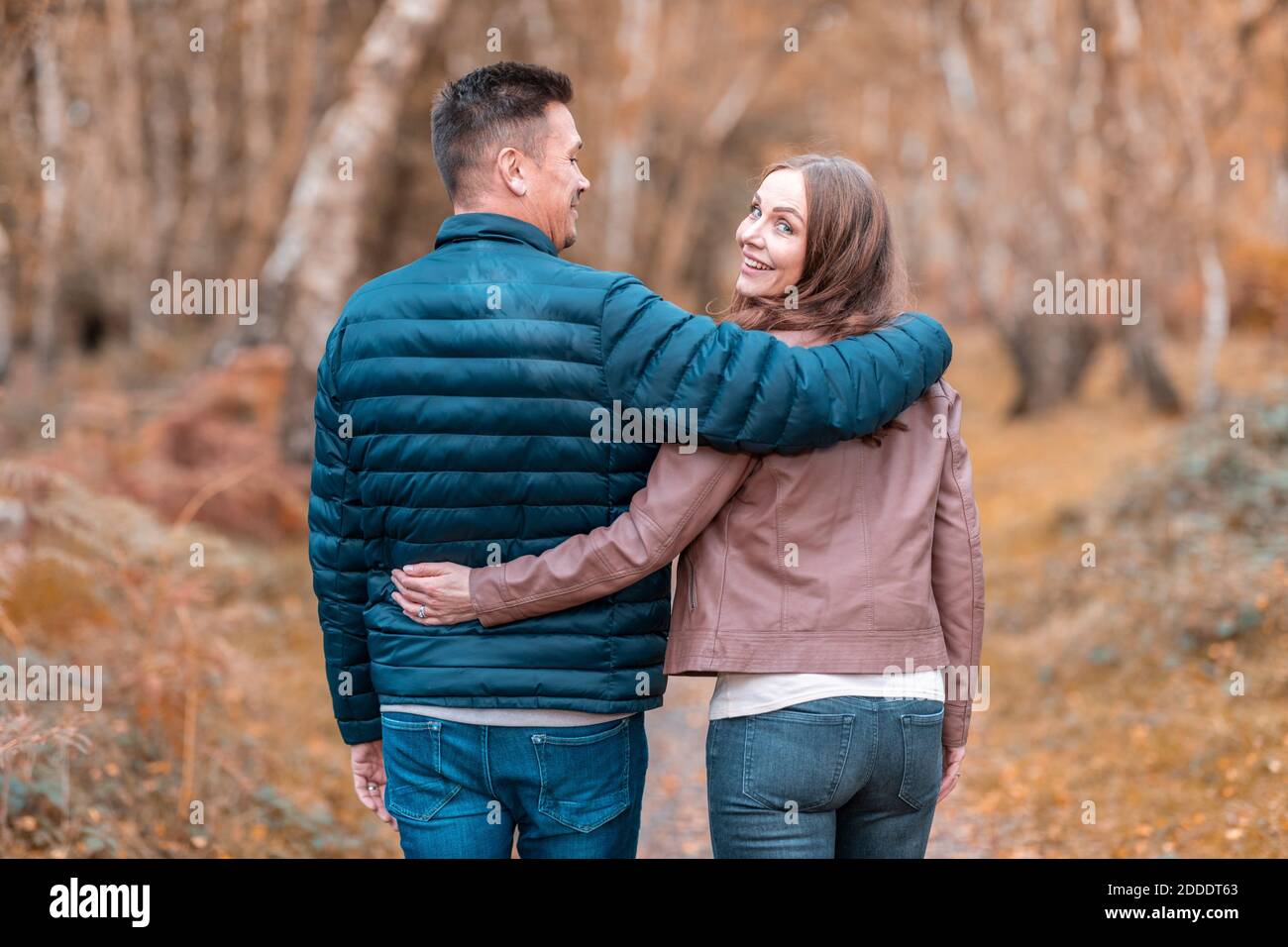 Felice coppia con armi intorno a camminare nel parco di Cannock Chase durante l'autunno Foto Stock