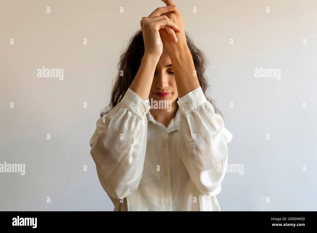 Modello femminile in posa con le mani aggrappate alla parete Foto Stock