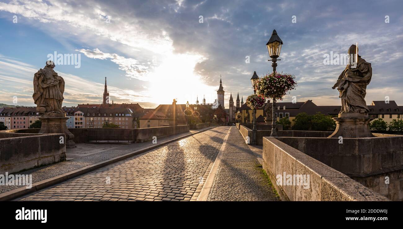 Germania, Baviera, Wurzburg, ponte Alte Mainbrucke vuoto al tramonto nuvoloso Foto Stock