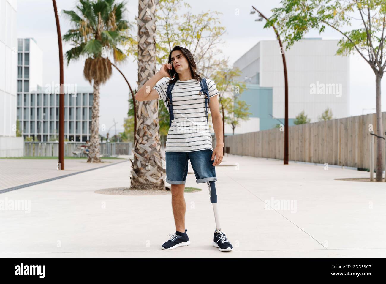 Uomo con arto artificiale che parla su smartphone in città Foto Stock