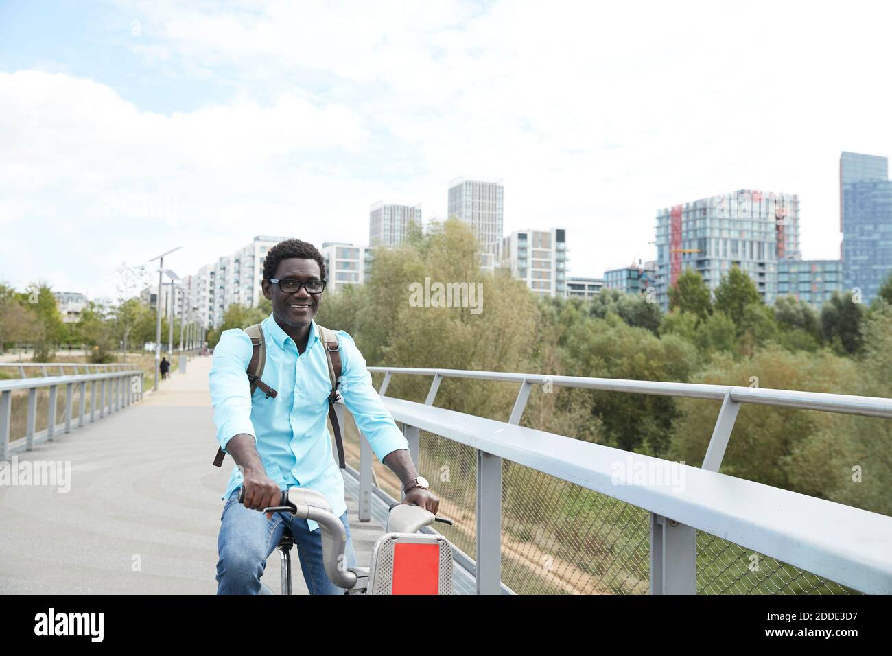 Uomo sorridente che si spostava su strada con la bicicletta in città Foto Stock