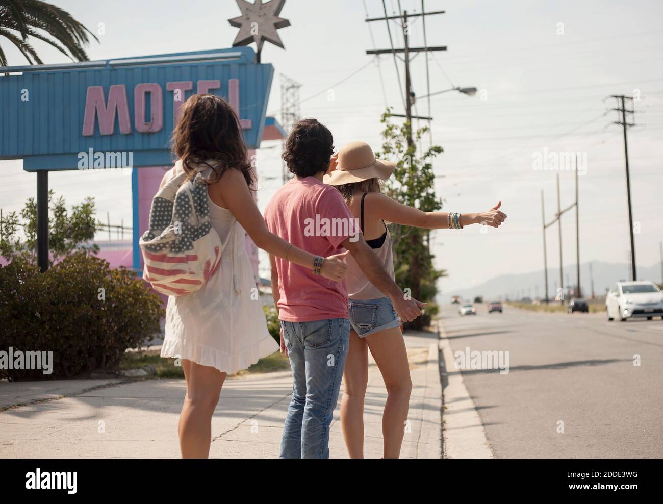 Vista posteriore dei tuoi amici mentre ti trovi sul marciapiede durante il giorno di sole Foto Stock