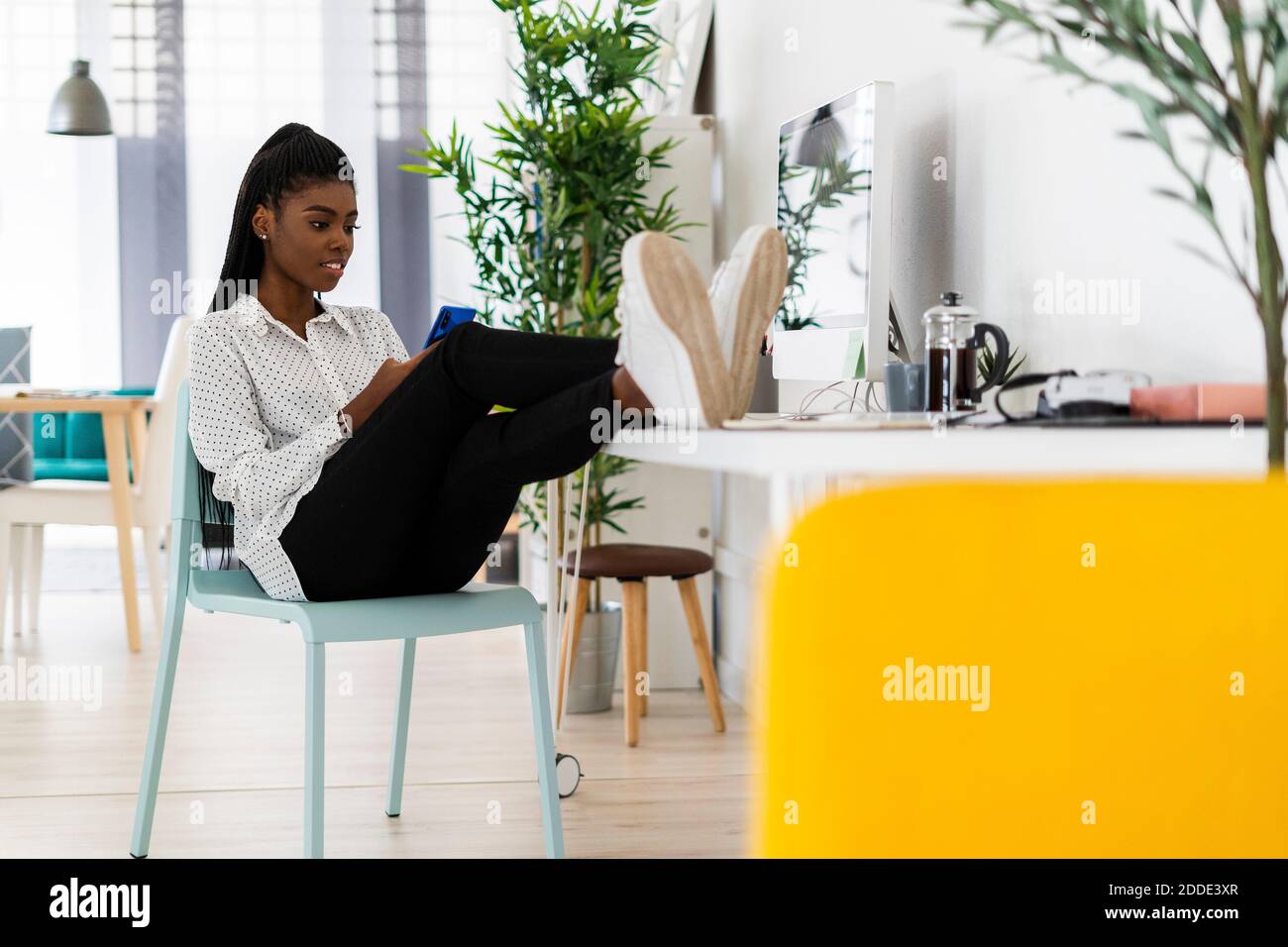 Messaggi di testo di una donna d'affari su uno smartphone seduto a casa Foto Stock