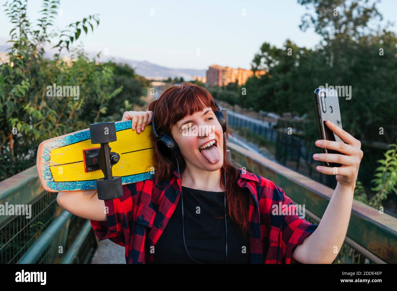 Giovane donna che si stacca la lingua fuori mentre parla selfie da smartphone Foto Stock