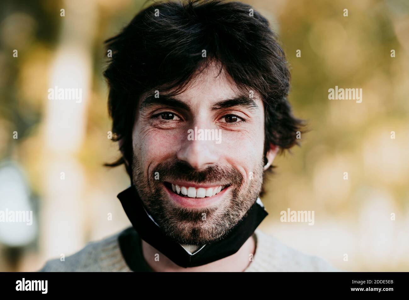 Uomo sorridente con maschera facciale in piedi nella foresta Foto Stock