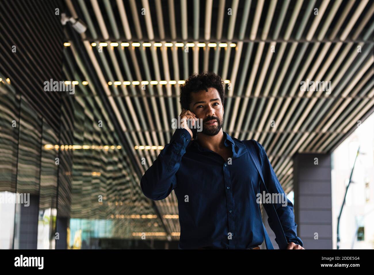 Uomo d'affari che parla su smartphone in città Foto Stock