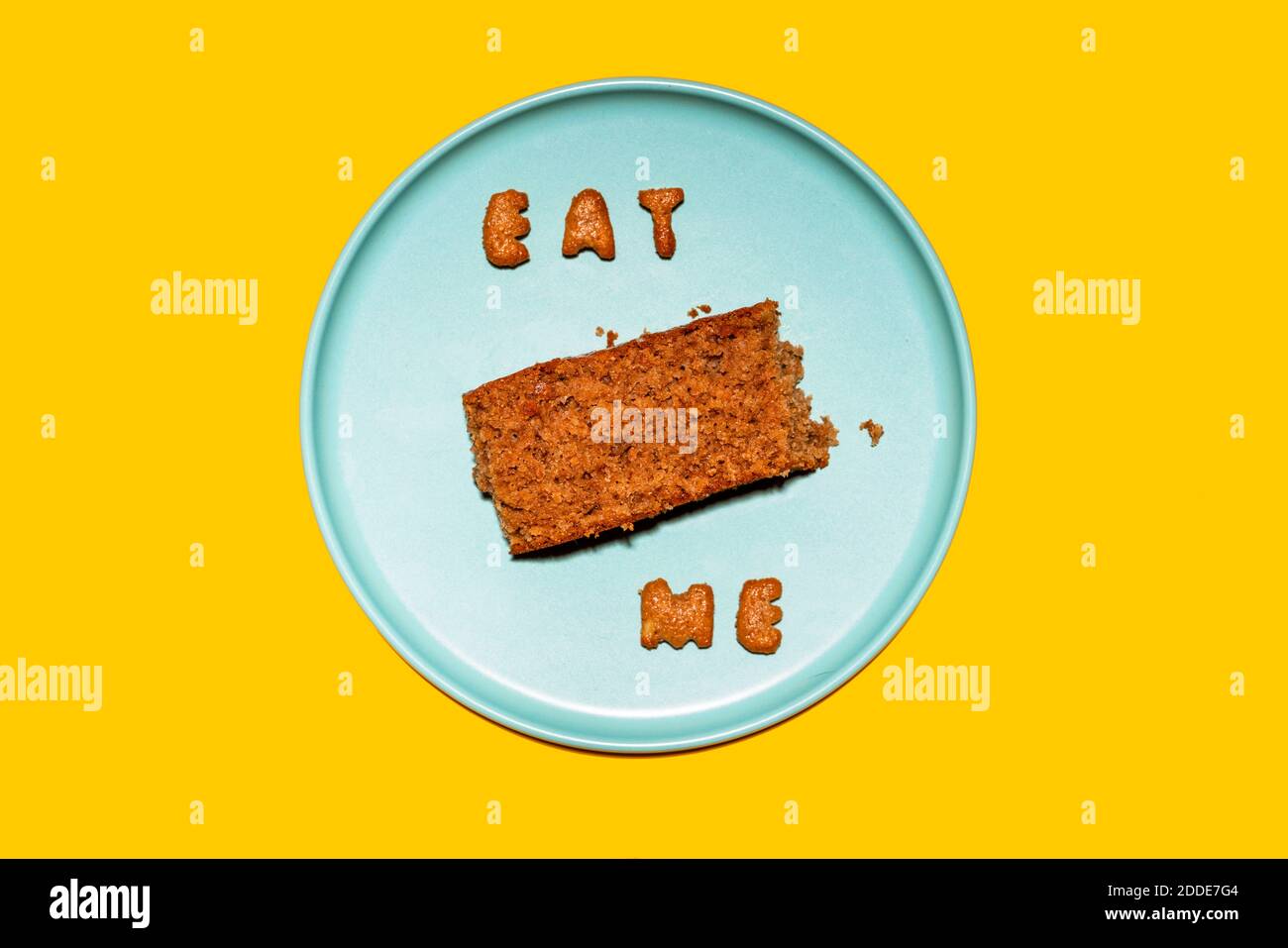 Fetta di torta su piatto blu con messaggio Eat Me in lettere biscotto Foto Stock