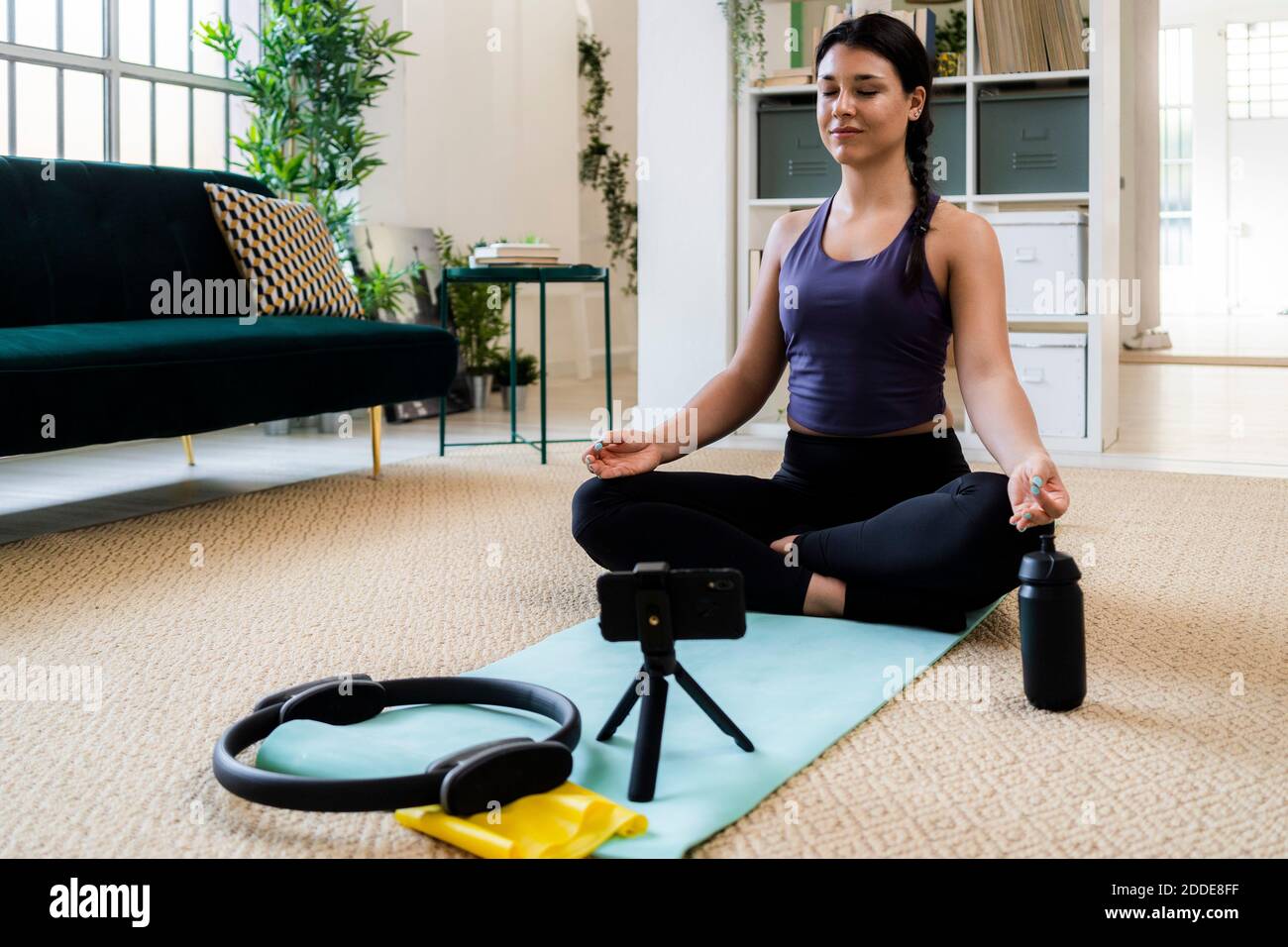 Atleta che medita mentre registra video a casa con la fotocamera Foto Stock