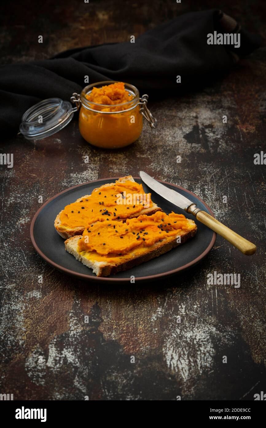 Piatto di fette di pane con vegano spalmato fatto con zucca, ceci e. semi di sesamo neri Foto Stock