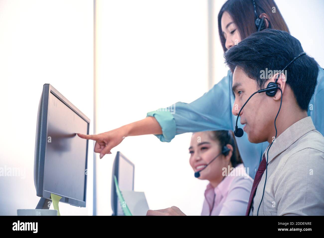 Gruppo di giovani uomini d'affari con cuffie e computer in ufficio. Concetto di assistenza aziendale. Foto Stock