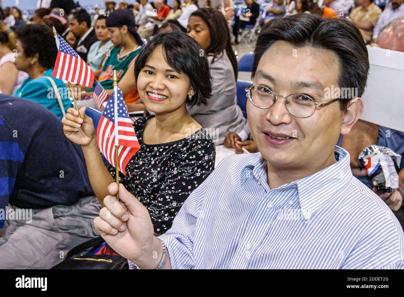 Florida,Miami Beach Convention Center,cerimonia di naturalizzazione,immigrati che detengono bandiera americana in miniatura,uomo asiatico donna maschio femmina sorridente nuovo cittadino Foto Stock