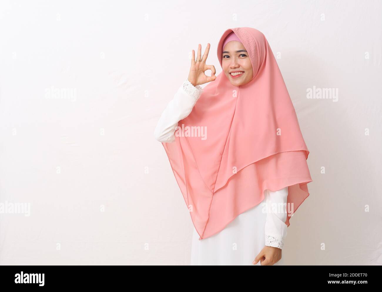 Un ritratto della donna musulmana asiatica felice che indossa un velo o un hijab con i gesti 'okay' della mano. Isolato su sfondo bianco con spazio per la copia Foto Stock
