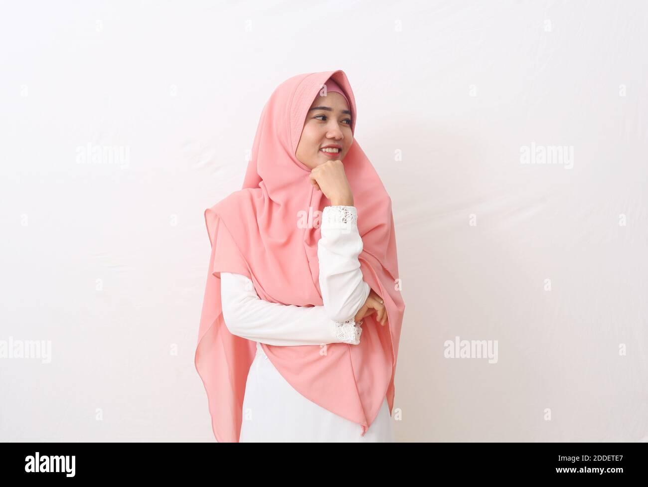 Un ritratto della donna musulmana asiatica felice che indossa un velo o un hijab che presenta e guarda lo spazio vuoto accanto a lei. Isolato su sfondo bianco con COP Foto Stock