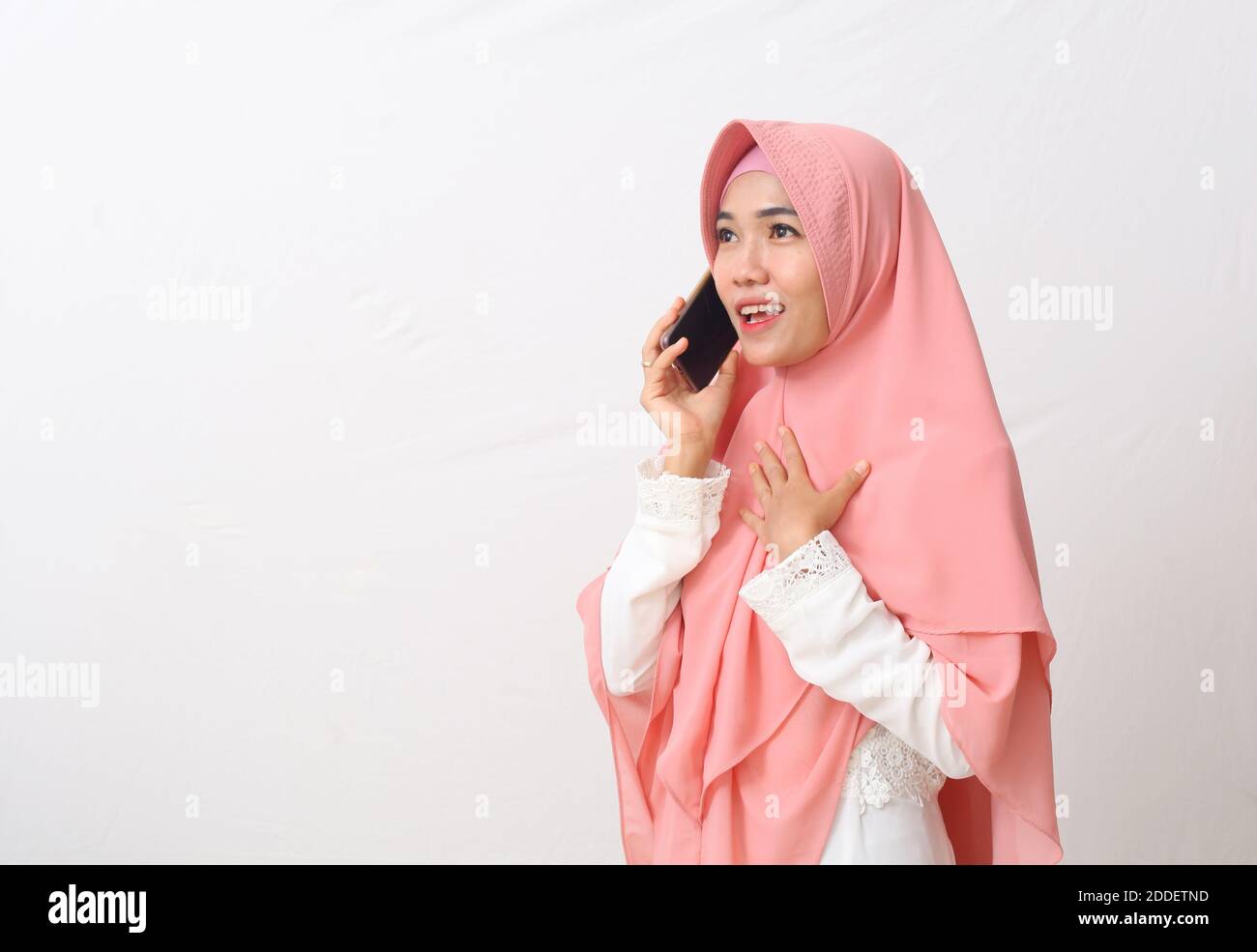 Un ritratto di felice musulmana asiatica che indossa un velo o un hijab mentre si parla al telefono, avendo una bella conversazione con qualcuno. Isolato su bianco Foto Stock