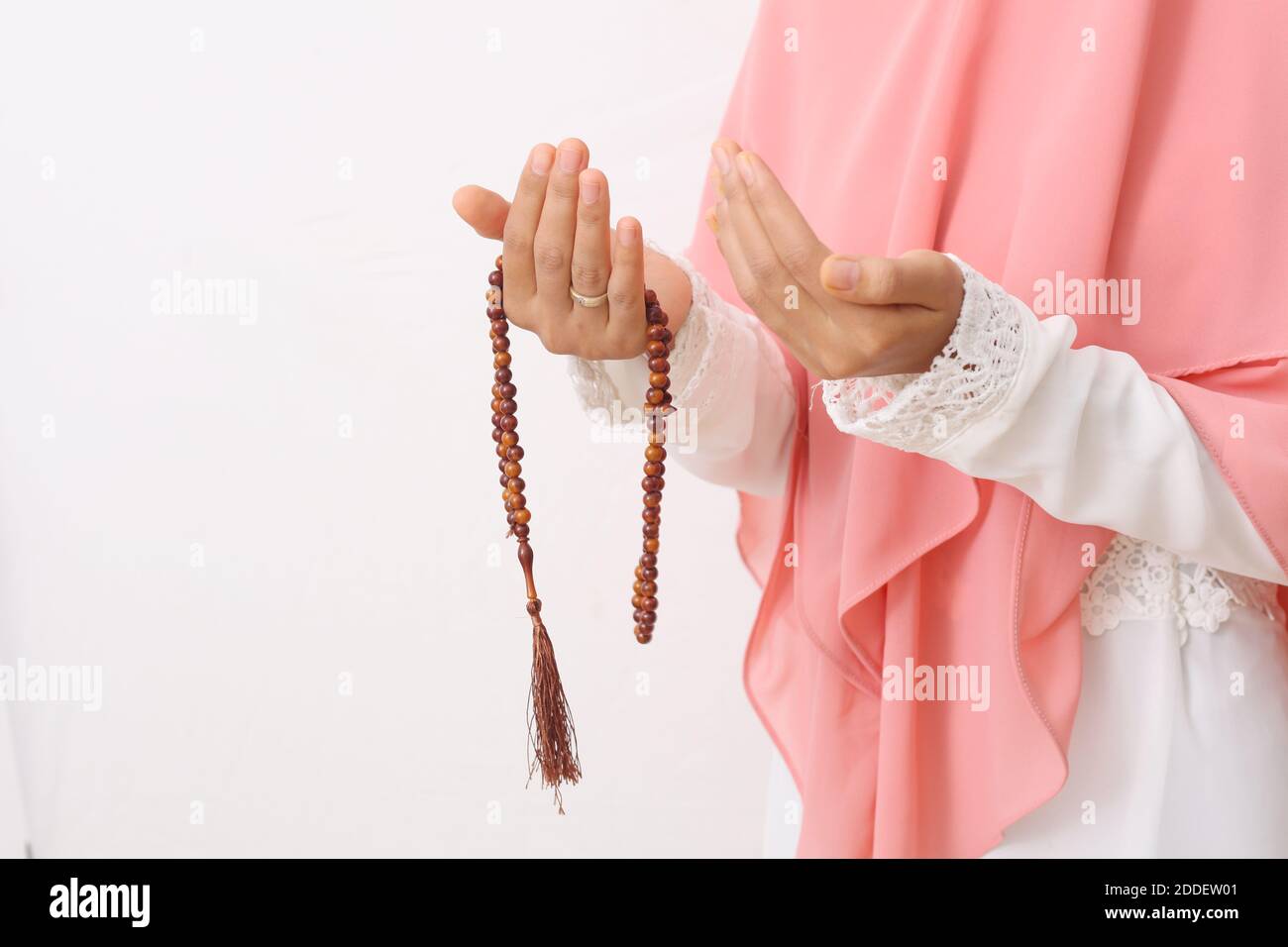 Un ritratto di una donna musulmana asiatica che indossa un velo o un hijab che prega con perline di preghiera sulla sua mano. Primo piano. Isolato su sfondo bianco con copia Foto Stock