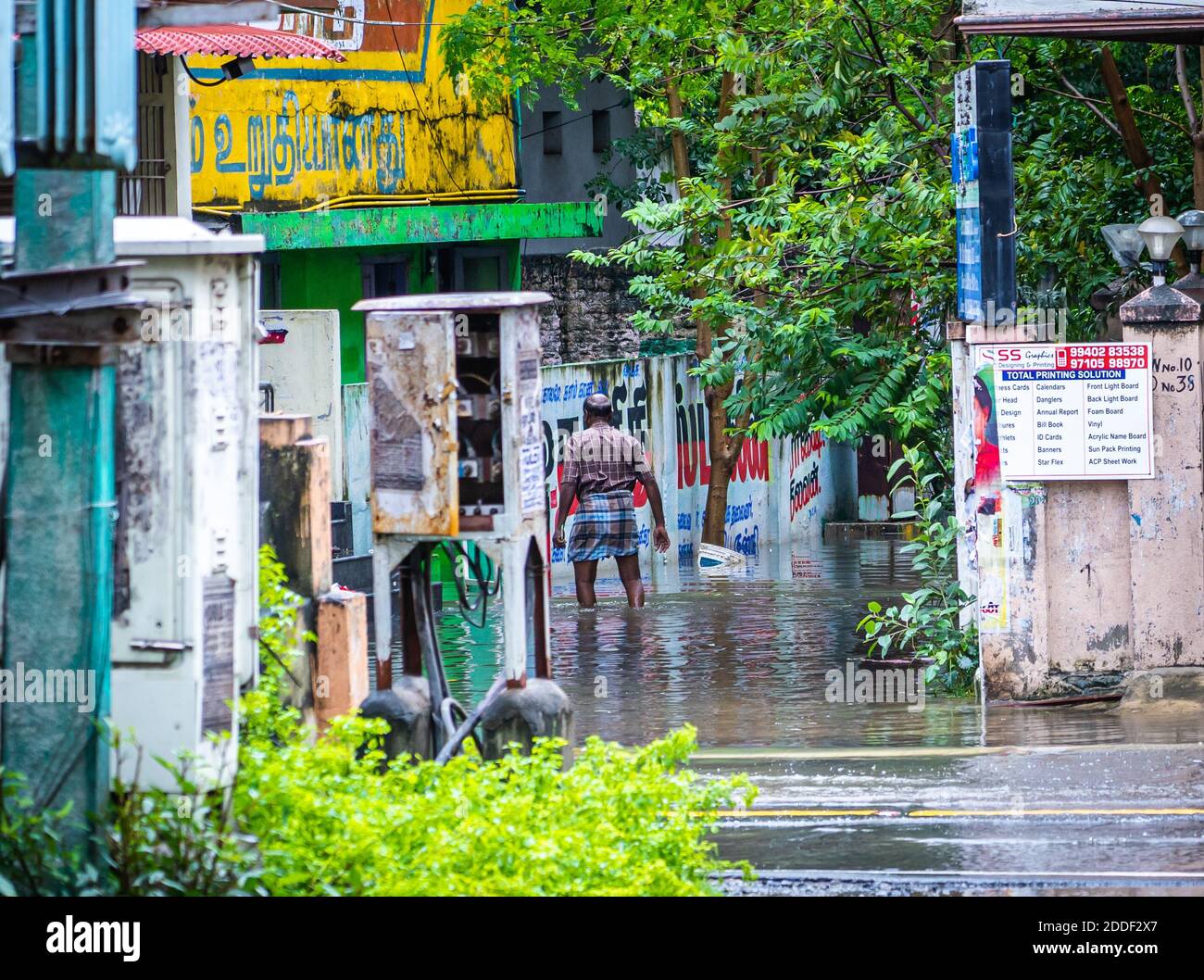 Un uomo sconosciuto cammina su una strada allagata. Le forti piogge del ciclone Nivar hanno causato inondazioni a Chennai. Foto Stock
